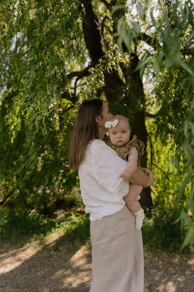 A mother holding her baby under a willow tree