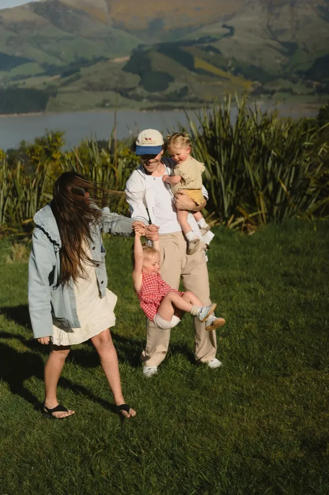 Parents swinging their daughter by the hands on the Port Hills